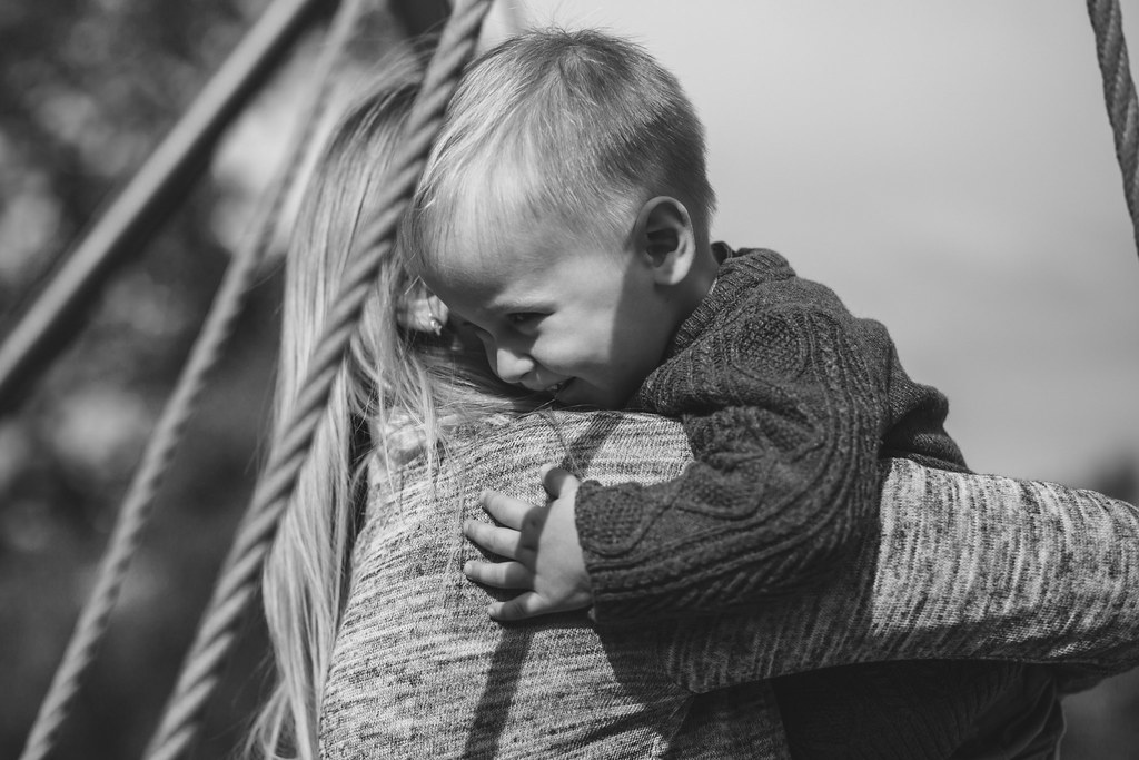 Un enfant blotti contre un adulte qui le porte